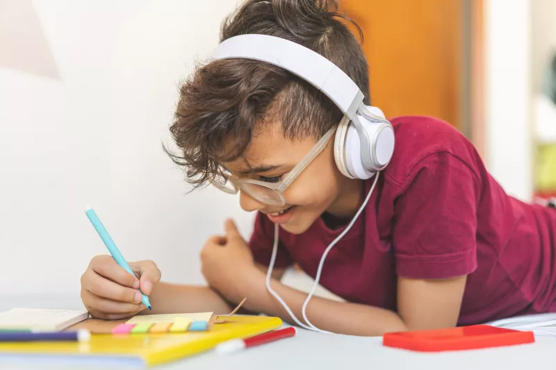 Boy working on schoolwork wearing headphones