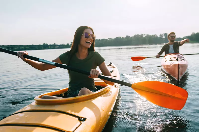 A Woman Kayaks With a Friend on a Lake 