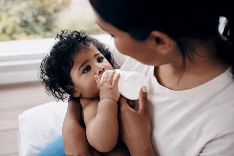 A mother feeding her baby milk in a bottle