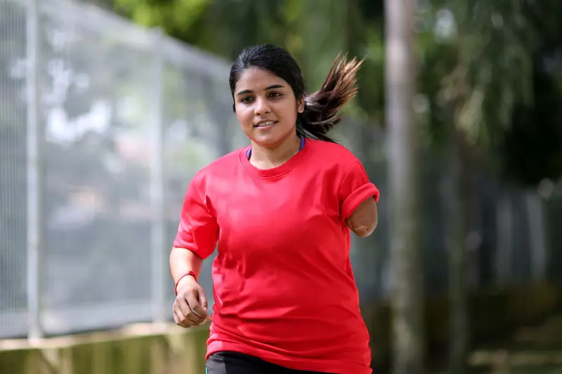 A Teenage Girl with One Lower Arm Runs in a Park.