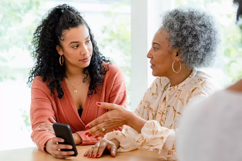Mother and Daughter Have a Discussion in the Kitchen While Holding a Cell Phone