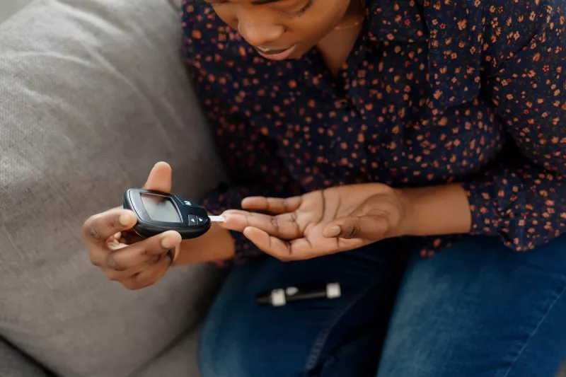 A Woman Tests Her Blood Sugar with a Finger Prick Glucose Device