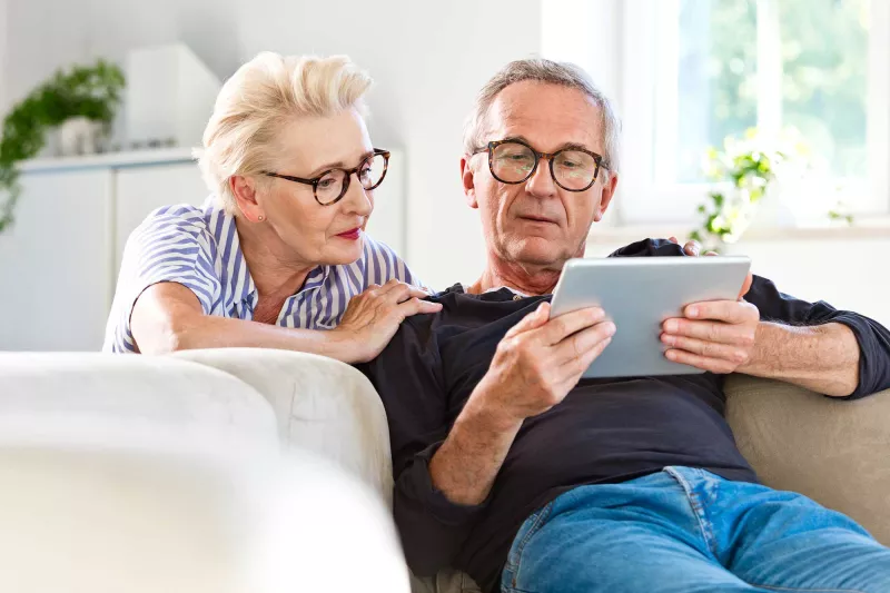 A senior couple focused on the tablet they carry