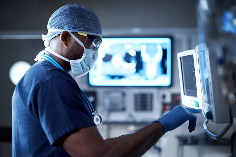 A Doctor Examines a Patient's Information on a Monitor During a Procedure