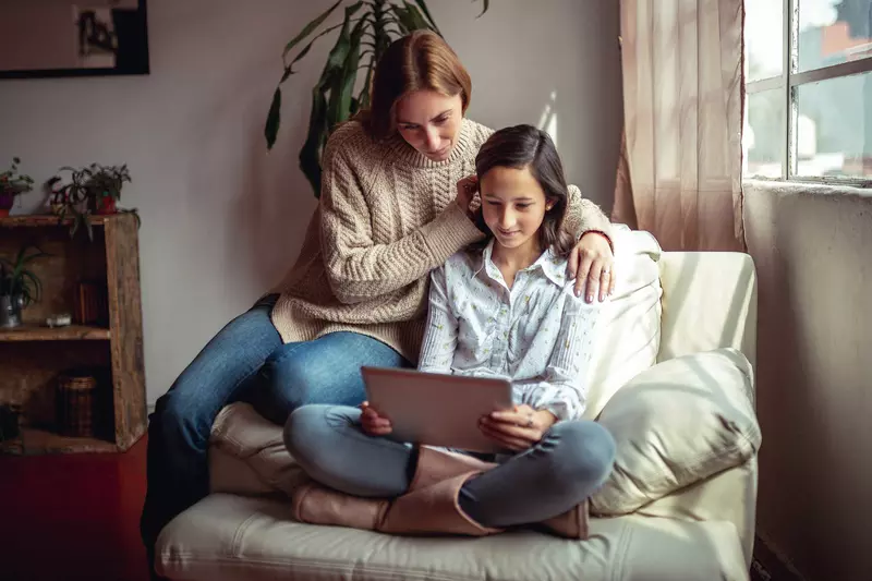 A mother and daughter reading from a tablet