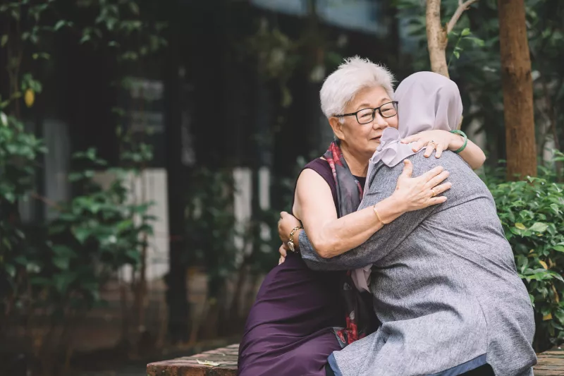 Two Women Embrace Outside in a Beautiful Nature Setting.