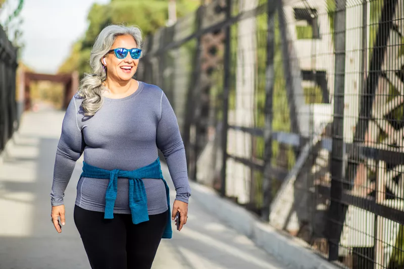 A Woman Walks Across a Pedestrian Bridge in the Fall