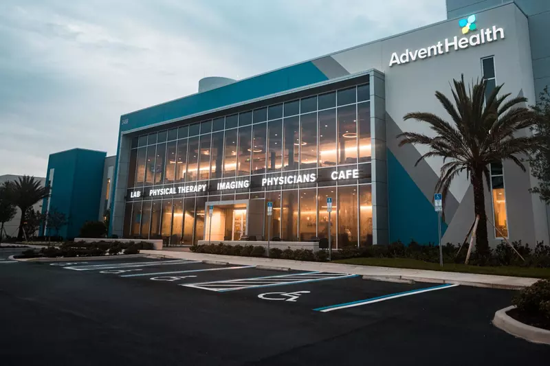 An Exterior Photo of an AdventHealth Health Park Building at Dawn with a Palm Tree in Front.