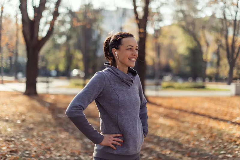 A Woman Smiles as She Takes a Break From a Jog in the Park