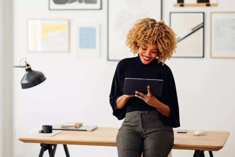 A slender, African American woman using a tablet at her office