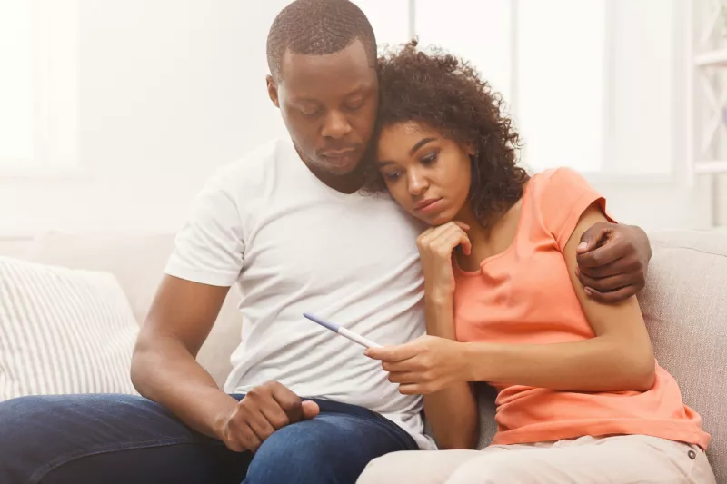 A Couple Embraces While Waiting for the Results of a Home Pregnancy Test.