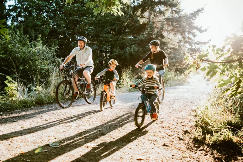 A Family Goes for a Bicycle Ride Through a Park on a Sunny Morning