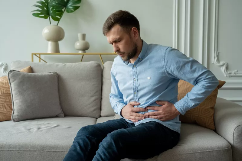 A Man Winces in Pain as He Hold's his Side