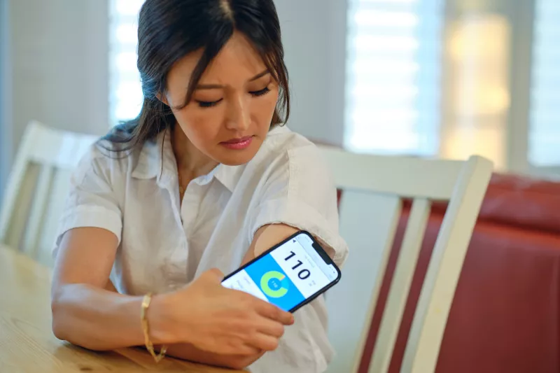 A Woman Checks Her Blood Sugar Levels at Her Kitchen Table.