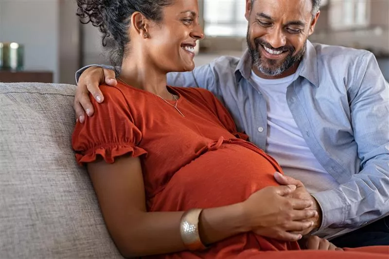 Pregnant couple sitting on couch