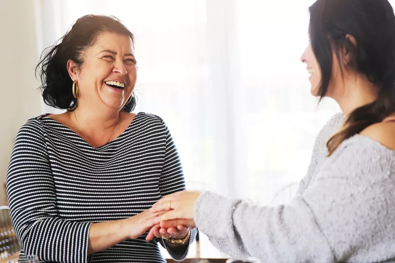 Two women, one holding another's hand, as she receives comfort from a friend after a cancer diagnosis.
