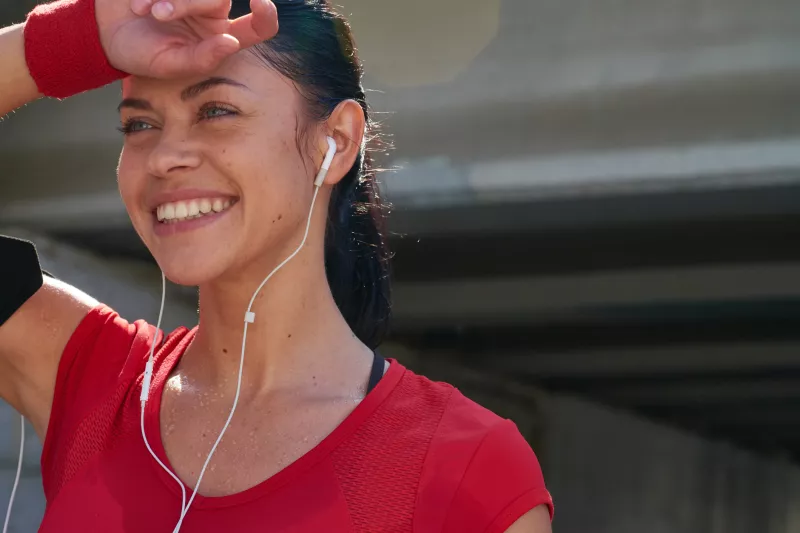 A woman with headphones in, dries off her forehead post workout.