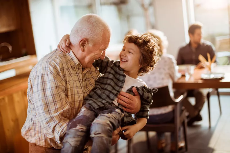 A grandfather holding his grandson on his lap.