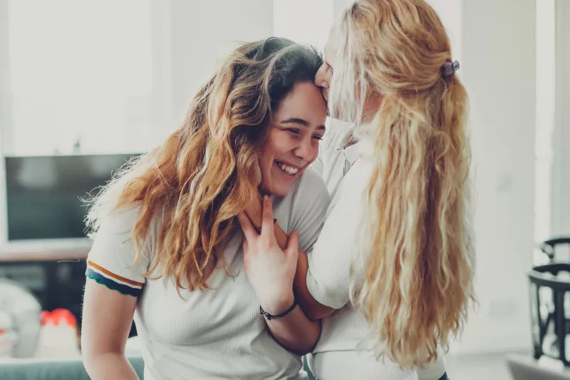 A mother kisses her teenage daughter.