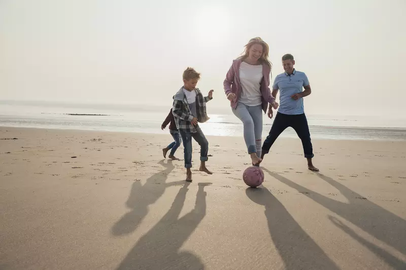 A family plays a friendly game of soccer on the beach