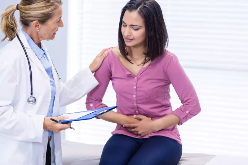 A woman experiencing stomach pain visits her doctor.