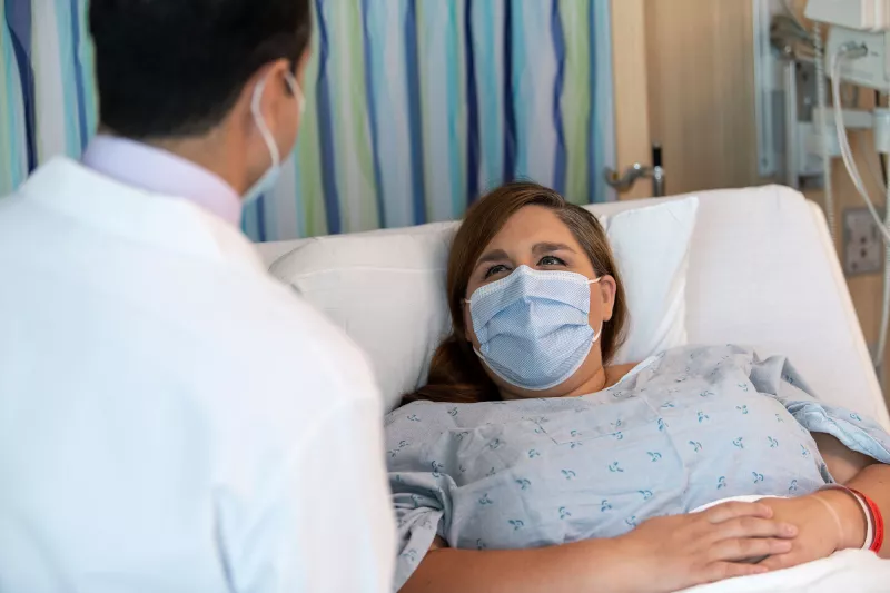 A doctor meeting with his patient while she lays in bed.