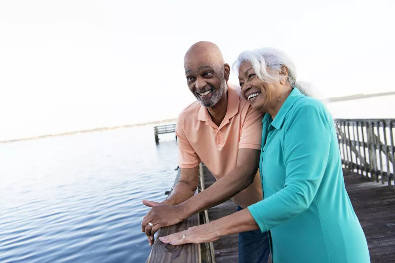 Older couple leaning on the pier looking at the lake