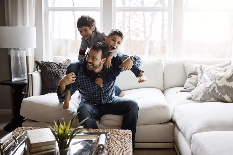 Dad playing with two boys on the couch