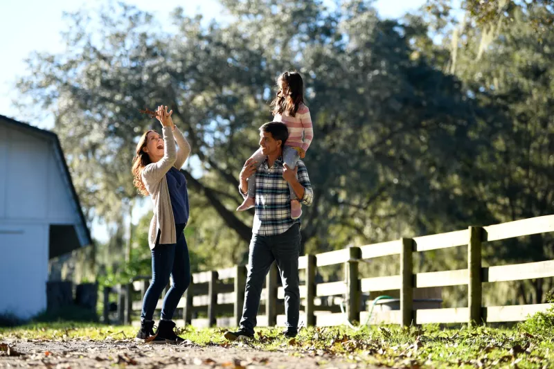 A mother, father, and small daughter walking around a ranch