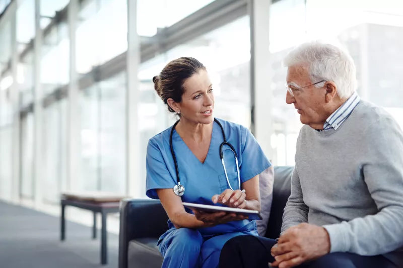 Nurse talking with older man at the hospital.