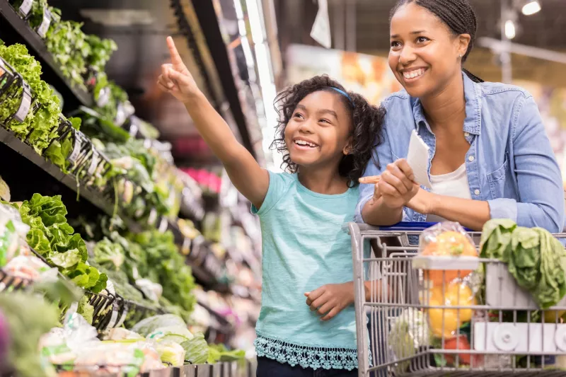 A mother and daughter shop for nutrient-rich vegetables at the supermarket.