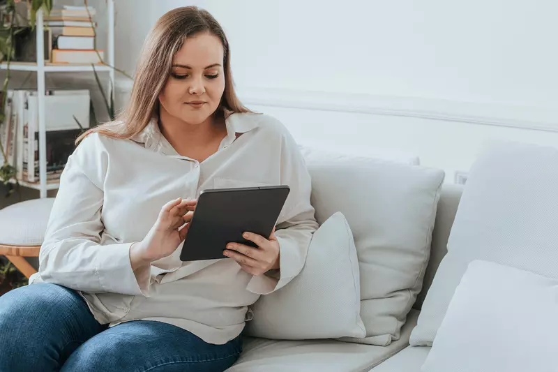 A woman using a tablet on her couch.