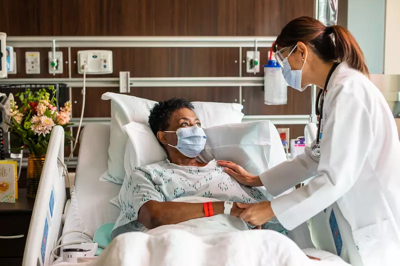A physician comforting a patient of color
