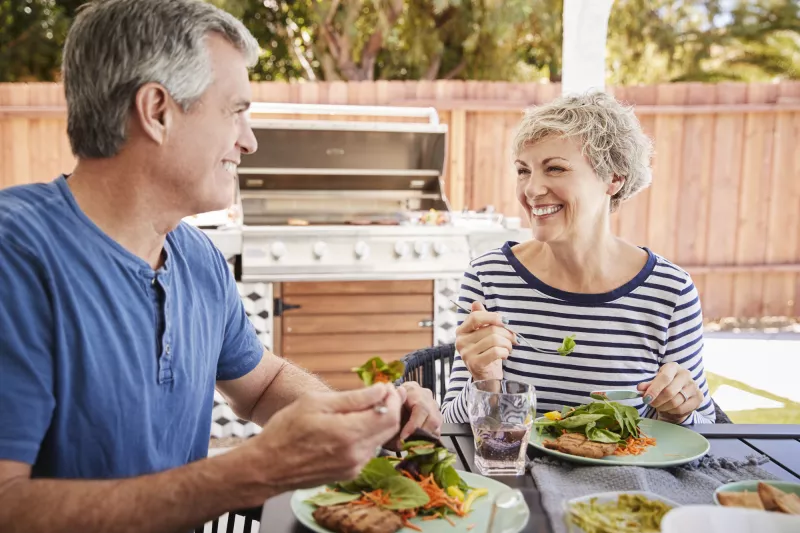 A couple eats a healthy meal together outside.