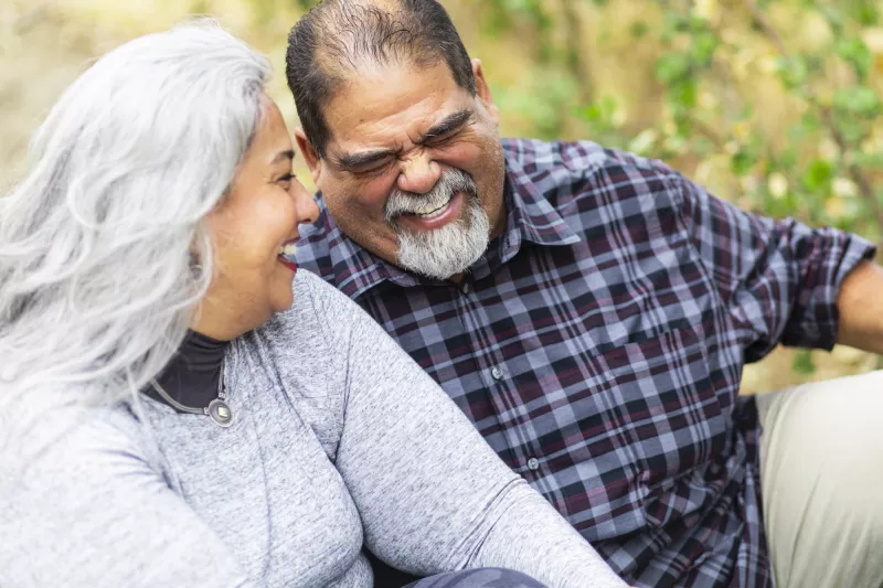 A couple laughs while on an outdoor picnic.