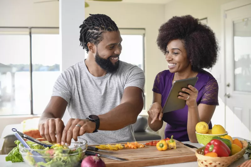 A couple making a salad from a recipe.