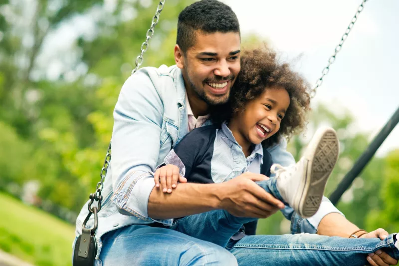 A dad swings with his giggling child.
