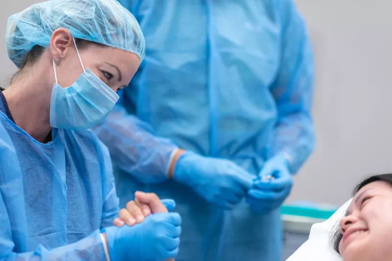 A doctor holding a patient's hand in the emergency room.