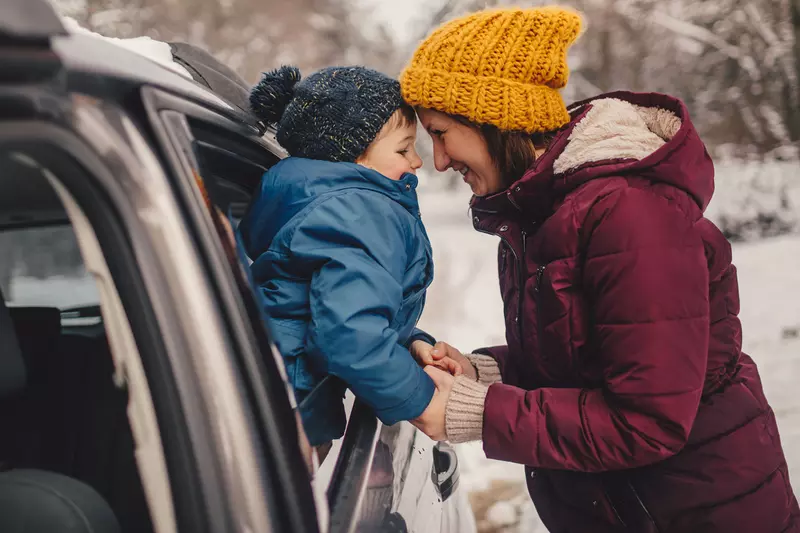 A mom prepares for a road trip with her family in the snow.