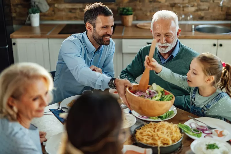 A family passing a salad at the dinner table.