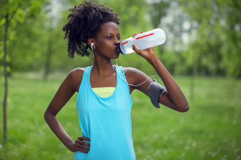 A woman taking a water break during her run.