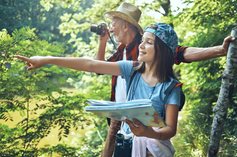 A grandfather hiking with his granddaughter.