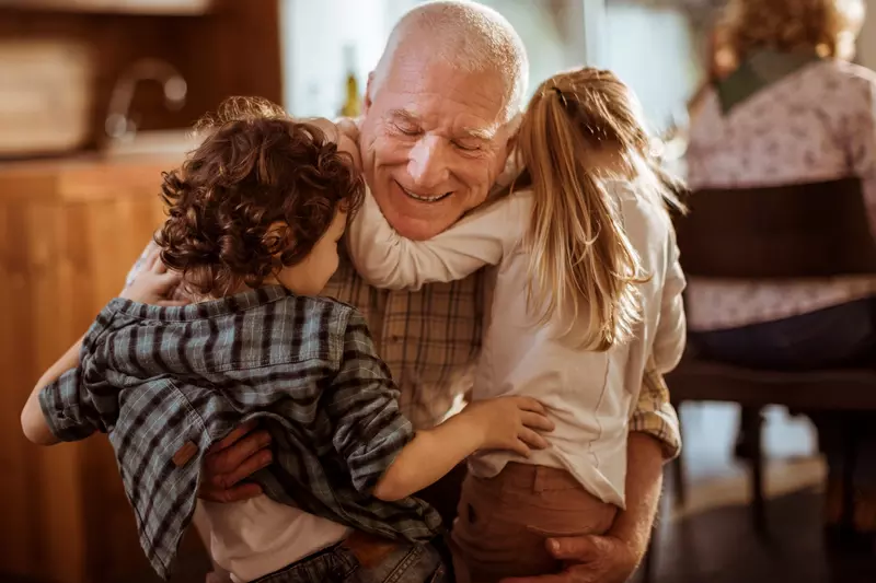 A grandfather hugs his grandchildren.