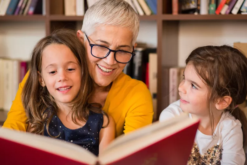 A grandmother reading to her granddaughters.