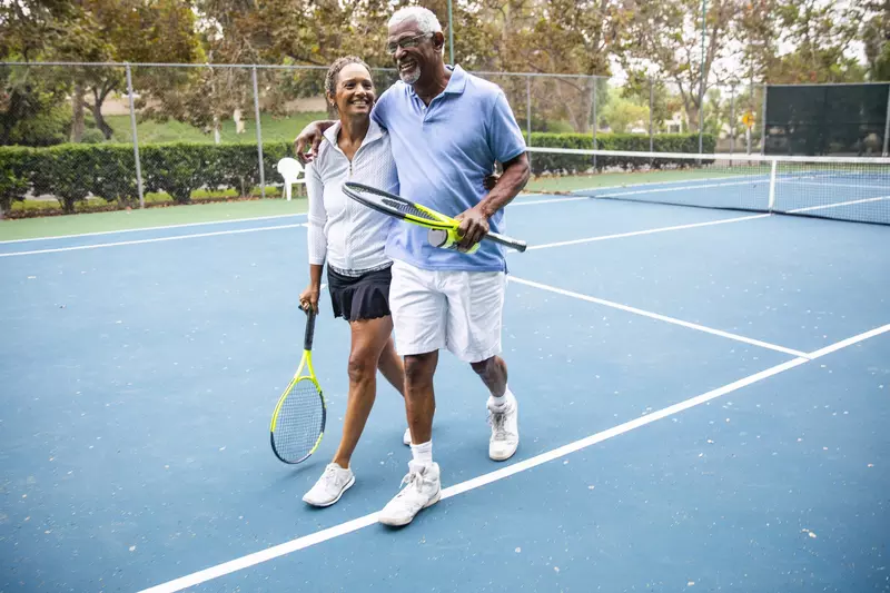 A happy couple plays a game of tennis.