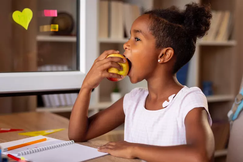 A little girl eats an apple for her healthy snack.