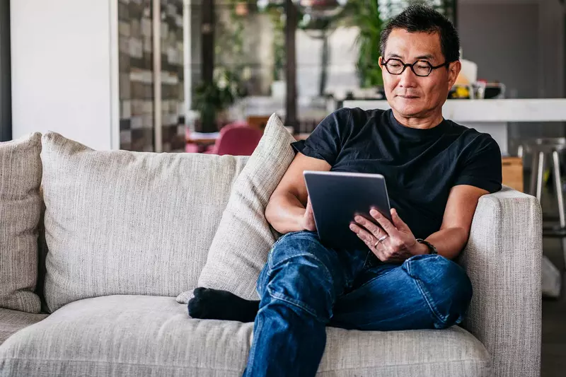 An asian man reading in his living room