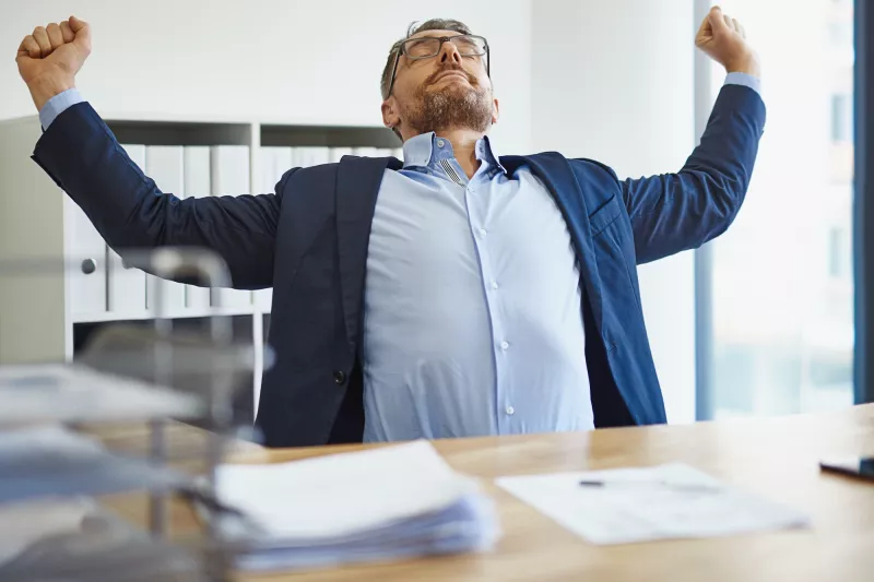 A man stretching at his desk.