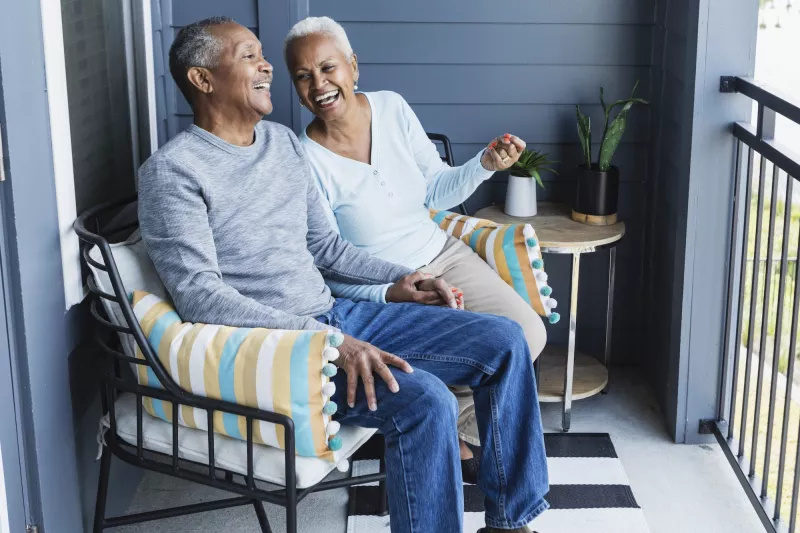 A couple laughing on their front porch together.