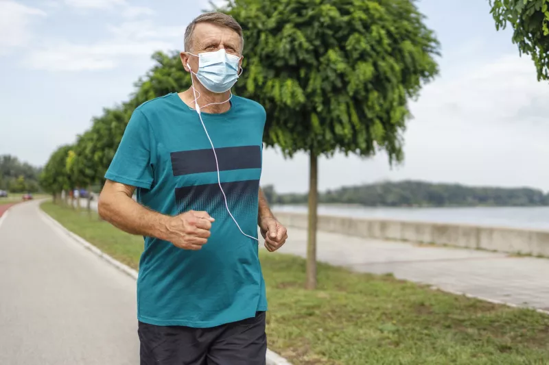 A man running outside wearing a mask.